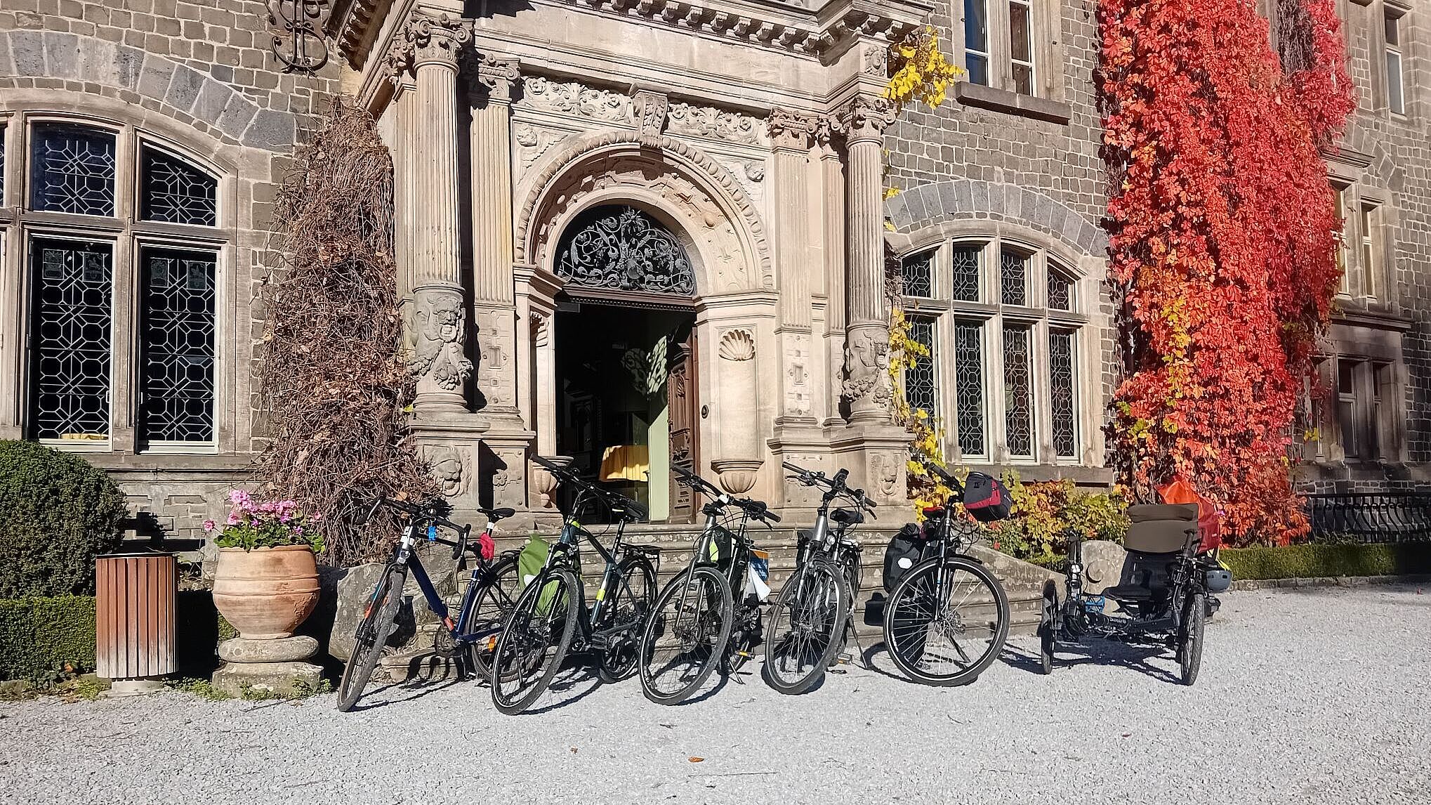 fahrräder stehen in Reihe vor dem Eingang zum Schloss Raisuchholzhausen in der Sonne.
