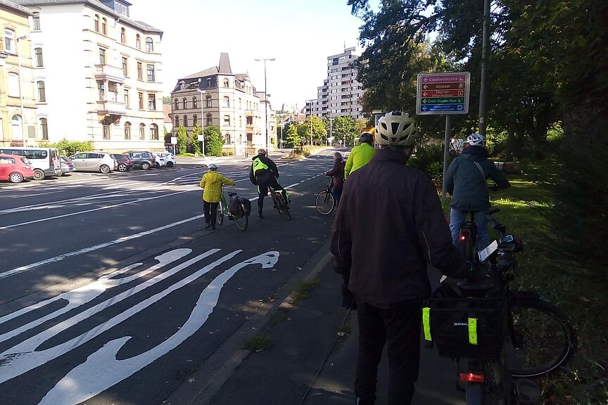 Schulung Ausfahrt Gisselberger Strasse Die Teilnehmenden der Schulung stehen an der Gisselberger Strasse und besprechen die Verkehrssituation sowie mögliche Verhaltensweisen.