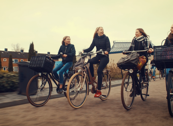 Bild aus dem Film: Vier Teenager-Mädchen fahren nebeneinander Fahrrad und unterhalten sich.